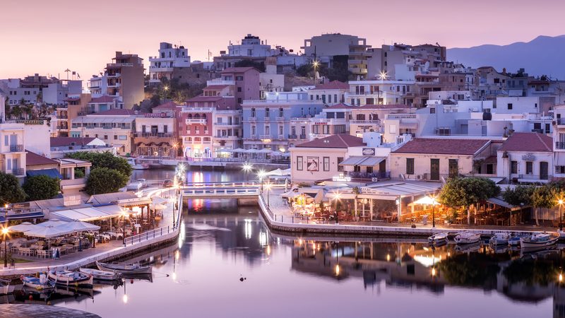 Lake Voulismeni with restaurants, shops and hotels near it at sunrise. Agios Nikolaos, Crete, Greece