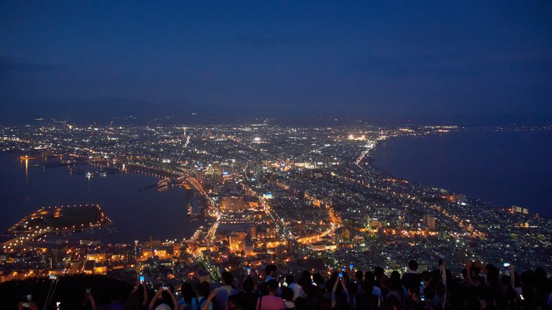 Crowd of visitors photographing the night view of Hakodate city from the summit of Mount Hakodate.