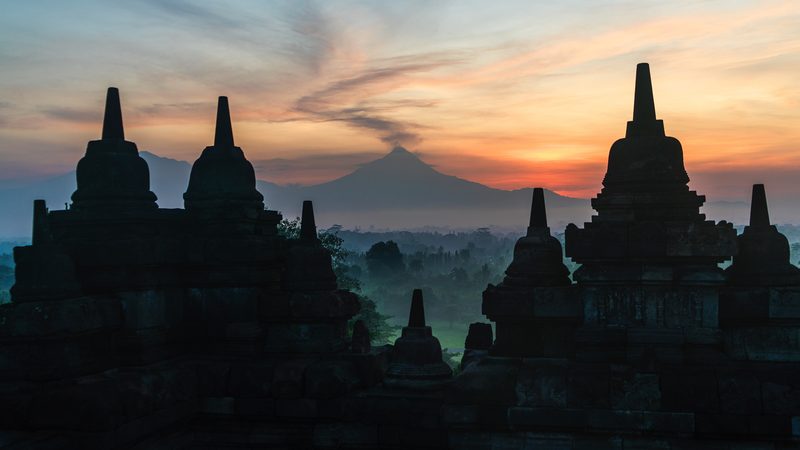 The sun rises over Borobudur Temple in Central Java. Mount Merapi is in the background.