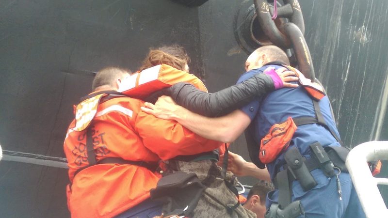 Crew members from Coast Guard Station Bellingham, Wash., assist Chiara D’Angelo, an activist, down from the an